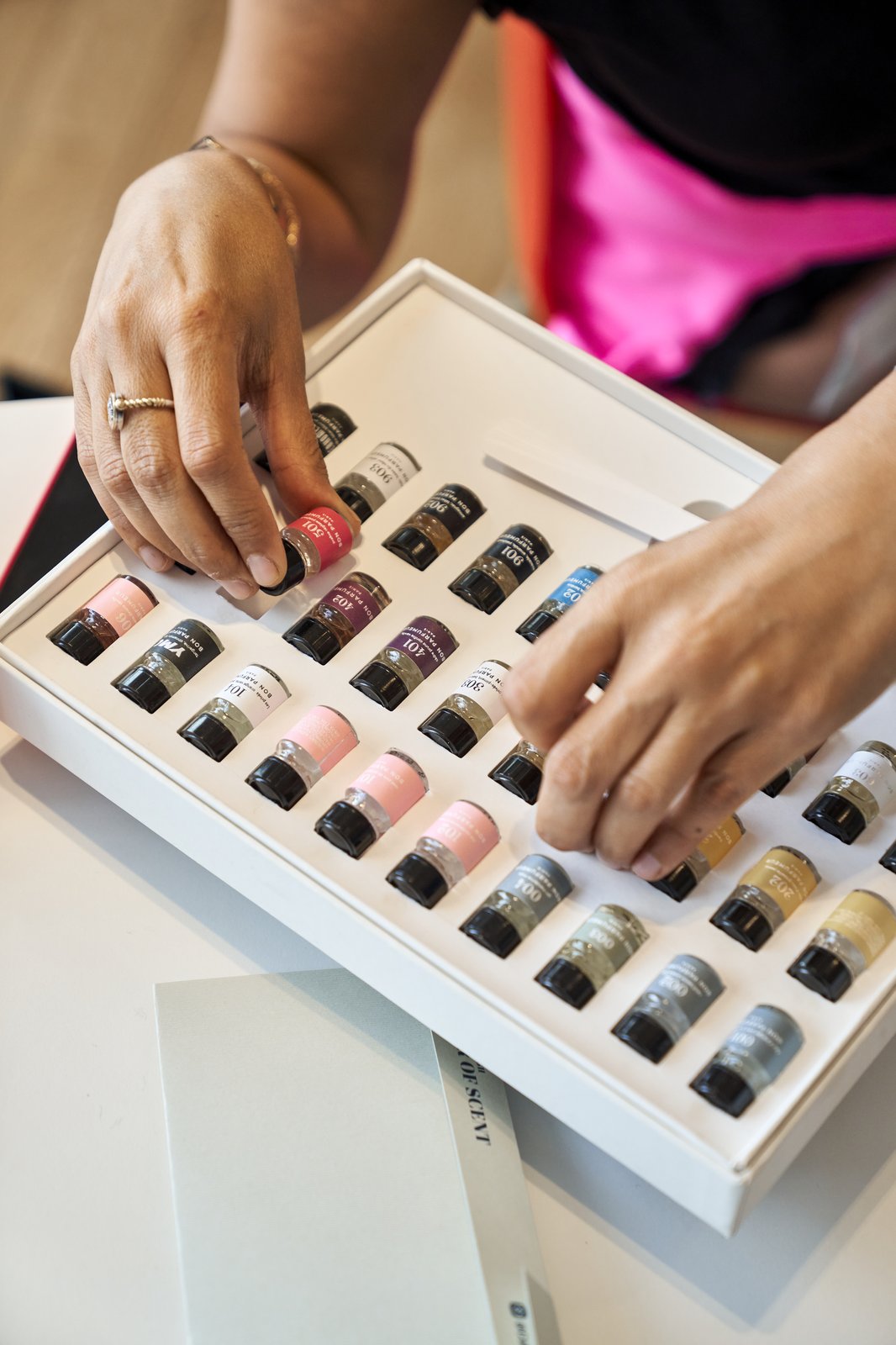 Hands selecting from a fragrance sample box